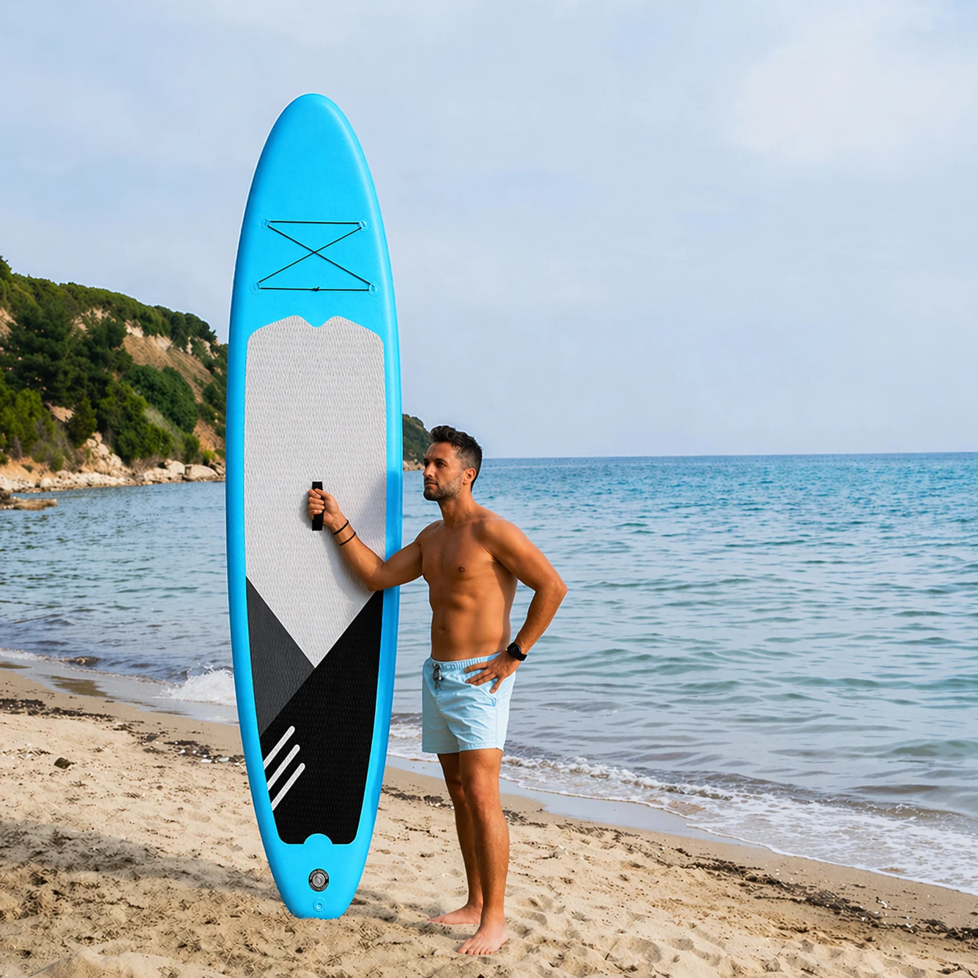 Mężczyzna trzymający pionowo deskę SUP na plaży